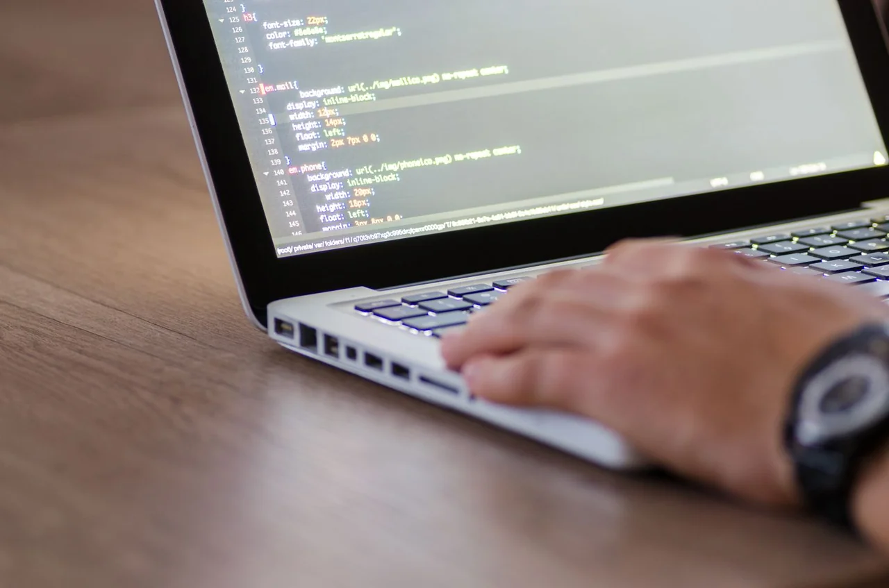 Web developer inspecting responsive HTML and CSS code on a monitor
