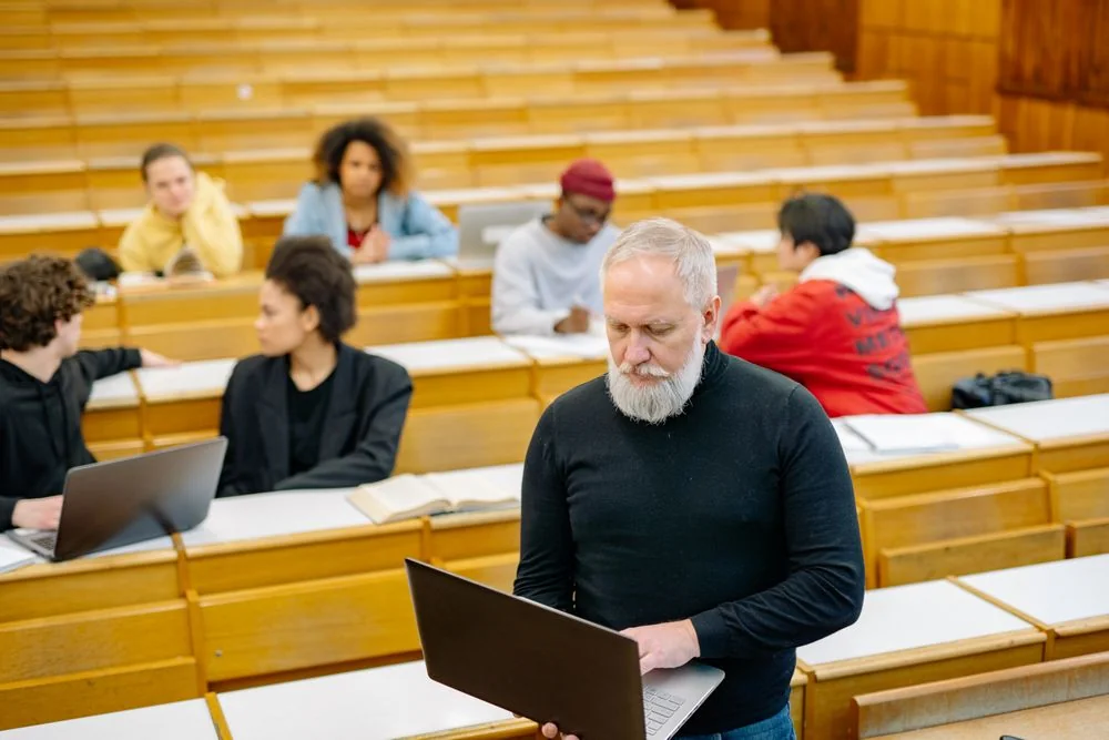 Adult learners using laptops in an open technical classroom with an instructor
