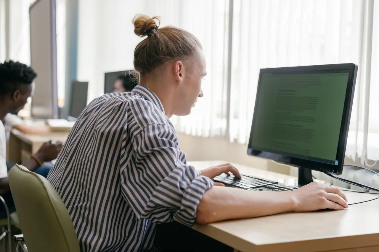 Focused adult student working on a modern computer workstation in an educational space